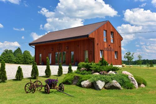 a large wooden barn with a garden in front of it at Sodyba "Bičiuliai" in Plungė