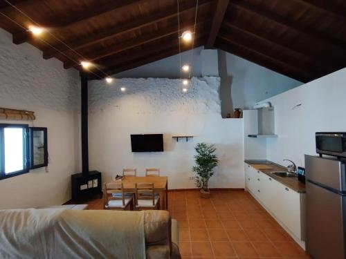 a living room with a table and a kitchen at Mi pequeña Abril in Grazalema