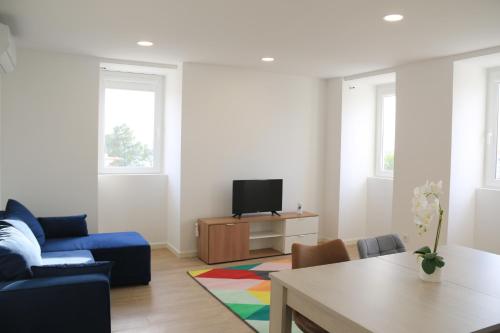 a living room with a blue couch and a tv at Maraveiro House in Aveiro
