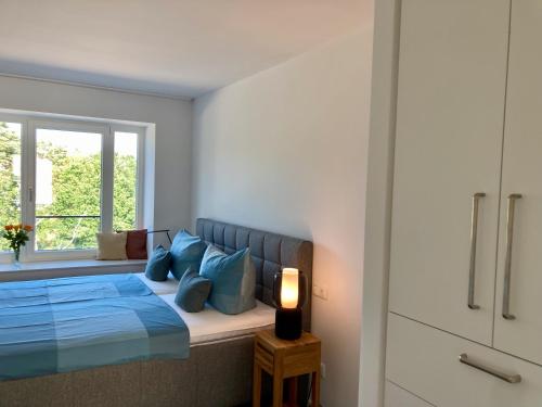 a bedroom with a bed with blue pillows and a window at Ein Katzensprung zum Meer - 3 Zi, 2 Bäder, Balkon in Binz
