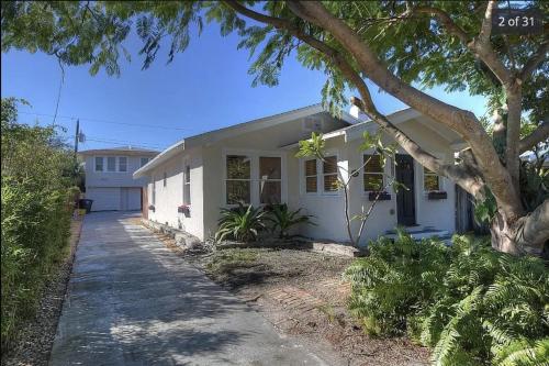 Una casa blanca con un árbol delante. en The Grandview Collection - FL Ave en West Palm Beach