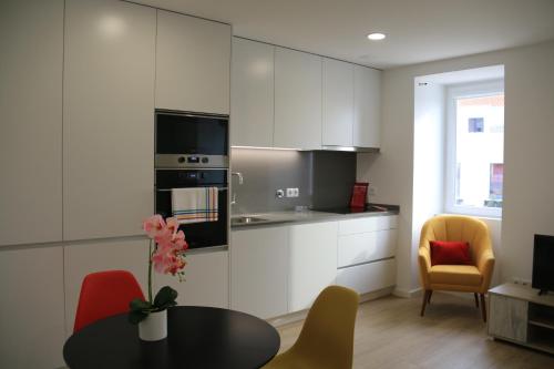 a kitchen with white cabinets and a table and chairs at Maraveiro House in Aveiro