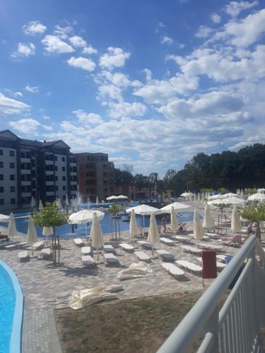 a pool with white umbrellas and chairs next to a resort at Studio Mišel in Vrnjačka Banja