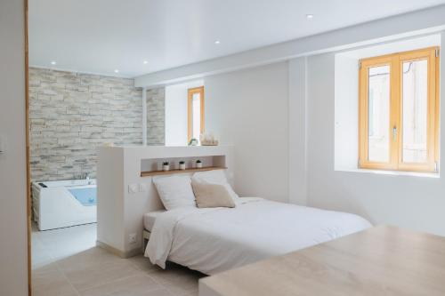 een witte slaapkamer met een bed en een bad bij Magnifique Loft Balnéo Hammam #3 in Embrun