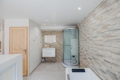 baño con ducha y pared de piedra. en Magnifique Loft Balnéo Hammam #3 en Embrun