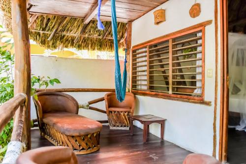 a porch with chairs and a table and a window at Zomay Beachfront Holbox in Holbox Island