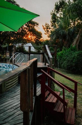 a wooden deck with a green umbrella and a pool at Complejo Familiar EL VIEJO MOLINO in Paso de la Patria