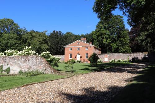 an old brick house with a stone wall and trees at Garden House at Woodhall Estate in Hertford