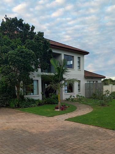 a white house with a palm tree in the driveway at En-suite, private room, free WIFI in Plett in Plettenberg Bay