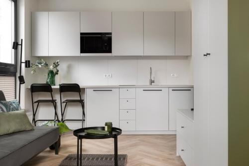 a kitchen with white cabinets and a couch and a table at Glow Apartments, Aparthotel Kołłątaja - Wrzeszcz in Gdańsk