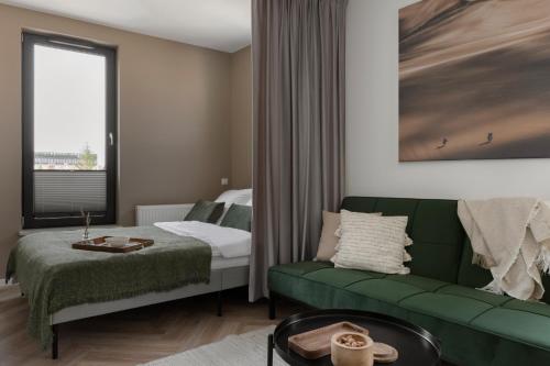 a living room with a green couch and a bed at Glow Apartments, Aparthotel Kołłątaja - Wrzeszcz in Gdańsk