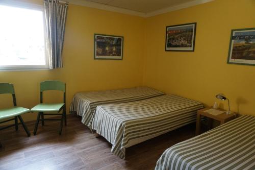 a room with two beds and a chair and a window at Gîte des Grands Causses in Millau