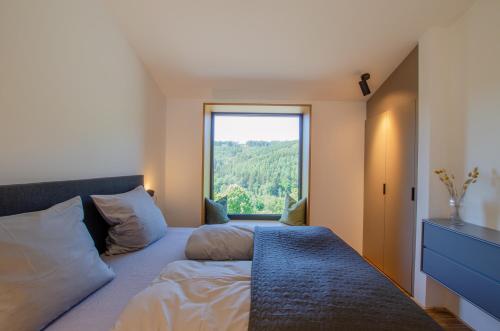 Schlafzimmer mit einem Bett und einem großen Fenster in der Unterkunft Sauerland Lodge - Haus Julius in Winterberg