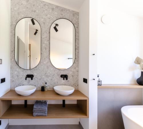 a bathroom with two sinks and two mirrors at Sauerland Lodge - Haus Julius in Winterberg