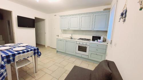 a kitchen with blue cabinets and a table with a tablecloth at Appartamento Perla Marina in Sottomarina