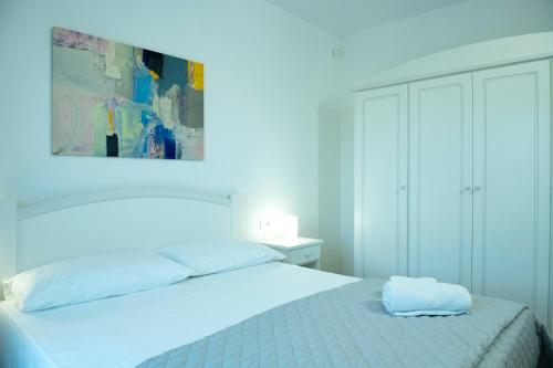 a white bedroom with a bed and a painting on the wall at Casa Antonello in Golfo Aranci