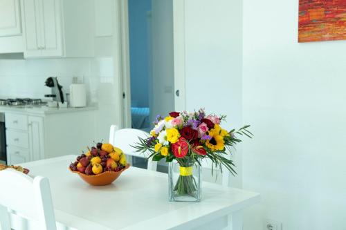 a vase of flowers on a table with a bowl of fruit at Casa Antonello in Golfo Aranci