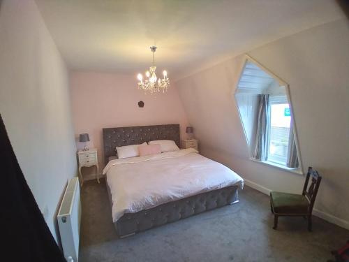 a bedroom with a bed with a chandelier and a window at Sea View Cottage, 2 bedrooms with stunning views in Cobh