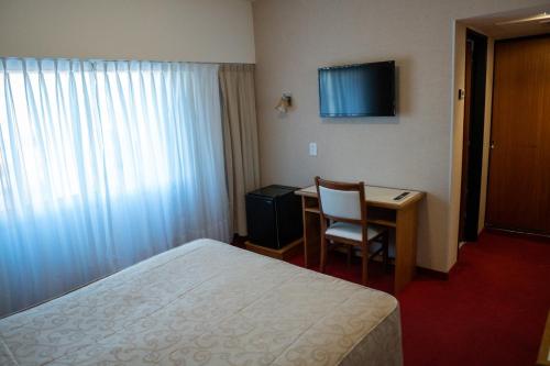 a hotel room with a bed and a desk and a television at Hotel Libertador in Trelew