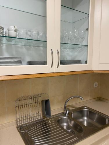 a kitchen sink with glasses in the cabinets at Maria Luísa in Olhos de Água