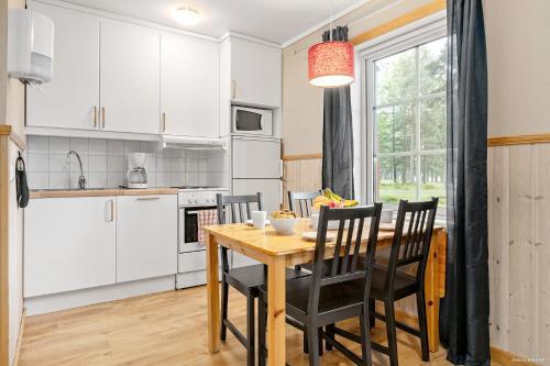 a kitchen and dining room with a wooden table and chairs at First Camp Moraparken - Dalarna in Mora