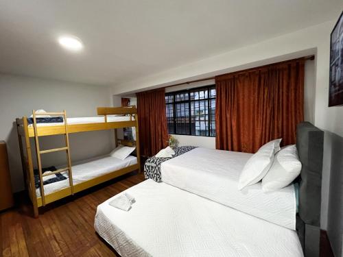 a bedroom with two beds and a bunk bed at Hostal Casa del Café in Bogotá