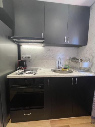 a kitchen with black cabinets and a sink at Св.Георги in Sapareva Banya