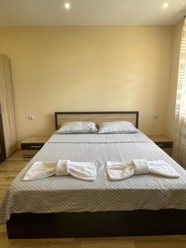 um quarto com uma cama com lençóis brancos e almofadas em Св.Георги em Sapareva Banya