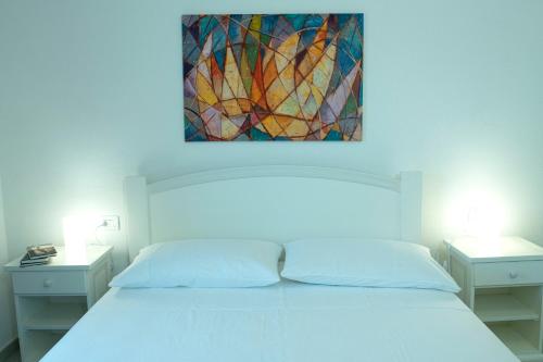 Un dormitorio con una cama blanca con un cuadro encima. en Casa Francesca, en Golfo Aranci
