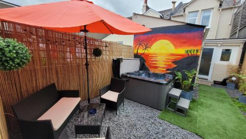 a patio with an umbrella and a hot tub at Near beach, Modern and Spacious 4 Bedroom House, Hot Tub, Wifi, Netflix, Parking in Paignton