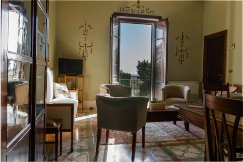 a living room with chairs and a table and a window at Baglio Spanò - Antiche Dimore di Sicilia in Petrosino