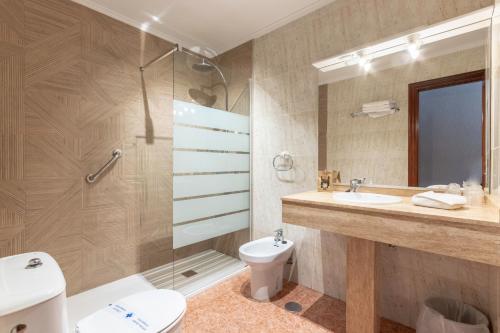 y baño con aseo, lavabo y ducha. en Hotel Gala, en Noja
