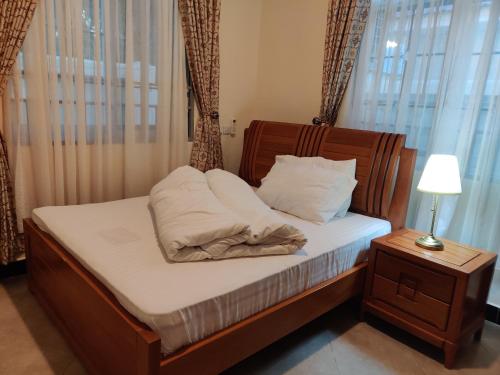 a bed with a wooden headboard and pillows on it at FAD Home & Apartments in Dodoma