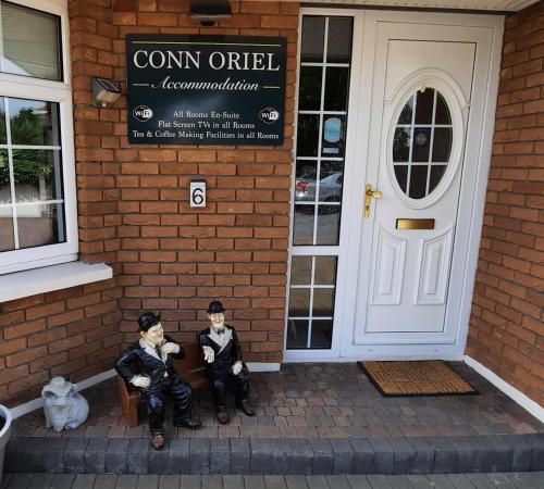 two figurines of two men sitting outside of a building at Conn Oriel in Tralee