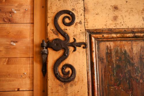 a black iron door knocker on a wooden door at Hotel Chasa Sofia in Scuol