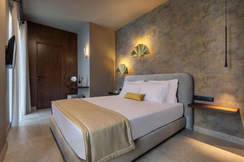 a bedroom with a large white bed and a wall at ASKLIPIOS LUXURY ROOMS in Nafpaktos