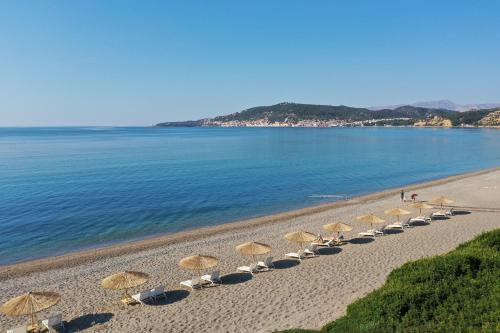 - une rangée de parasols sur une plage au bord de l'eau dans l'établissement Niriides Resort, à Gythio