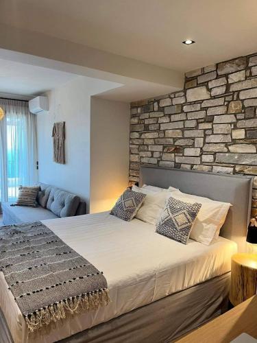 a bedroom with a large bed with a stone wall at Peri Elxis Luxury Suites in Mouresi