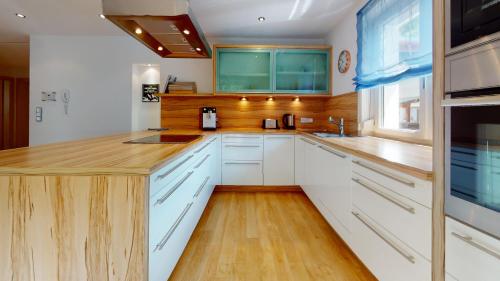 a kitchen with white cabinets and a wooden counter top at FERIENWOHNUNGEN TANJA - dein Wohlfühlhaus in Kappl in Kappl