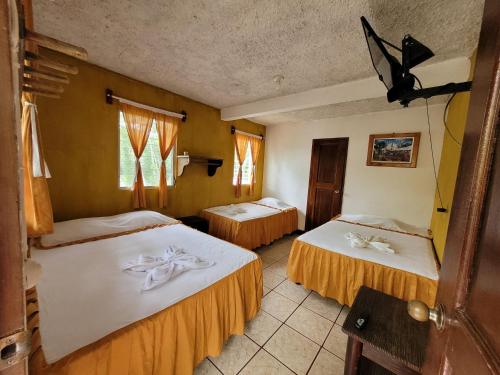 a hotel room with two beds and two windows at Hotel y Restaurante La Cabaña el Viajero in Castillo de San Felipe