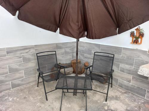 two chairs and a table with an umbrella at Apartamento a minutos caminando del Aeropuerto CDMX Terminal 1 in Mexico City