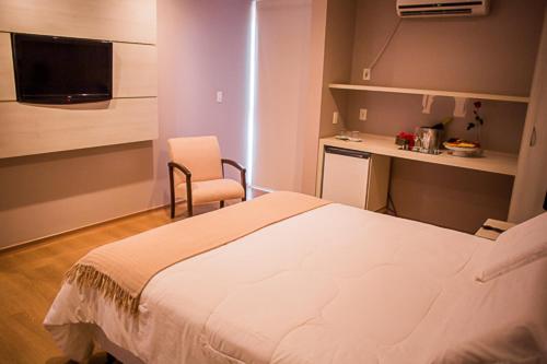 ein Schlafzimmer mit einem Bett, einem Stuhl und einem Schreibtisch in der Unterkunft Hotel Marques in Araras