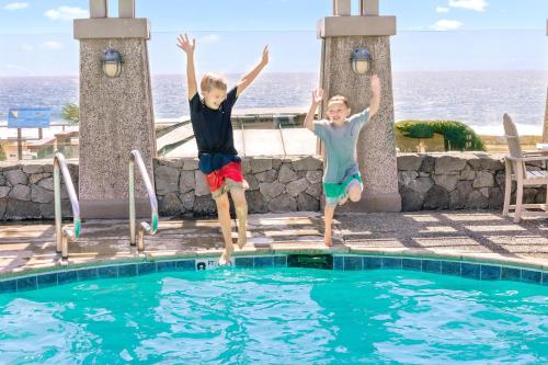 duas crianças a saltar para uma piscina em Sands by the Sea Motel em San Simeon