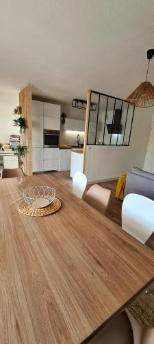 a living room with a wooden table and a kitchen at Appartement avec terrasse, parking et proche tramway in Montpellier