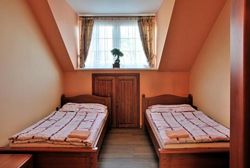 two beds in a small room with a window at Zámeček Kaliště in Poddubí
