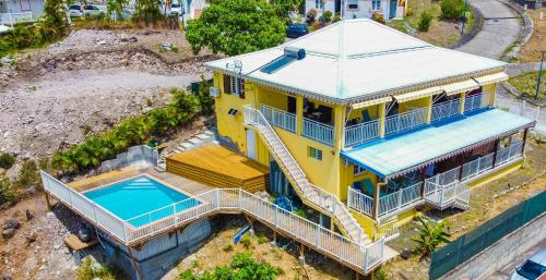 Cette chambre offre une vue sur une maison jaune dotée d'une piscine. dans l'établissement Ocean bleu 972 Orange N 2, à Les Anses-d'Arlet
