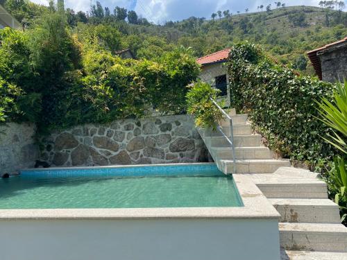 a swimming pool with stairs next to a stone wall at Douro Senses - Village House in Cinfães