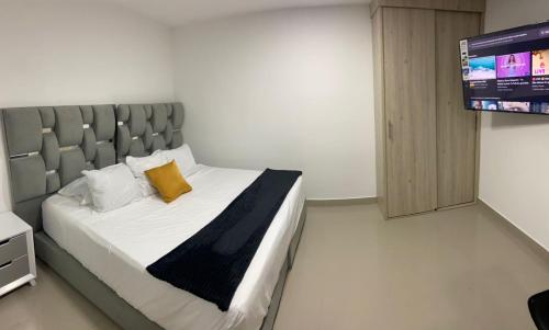 Aparta Suites 503 Granada Cali في كالي: غرفة نوم عليها سرير ومخدة صفراء