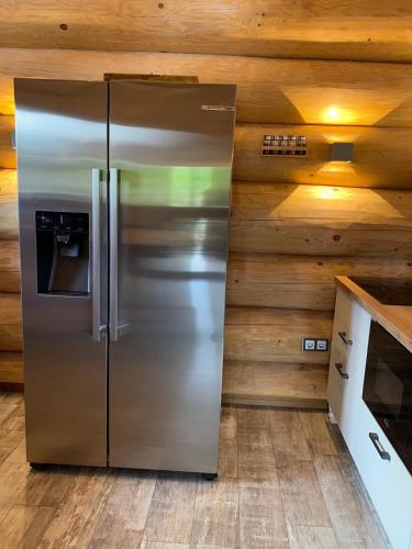 a stainless steel refrigerator in a kitchen with wooden walls at Waldstein Chalet in Zell im Fichtelgebirge