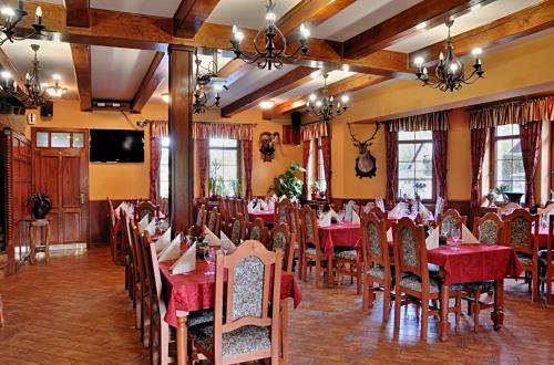 a restaurant with red tables and chairs and a flat screen tv at Zámeček Kaliště in Poddubí